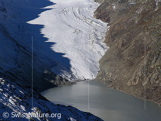 Foto: Blick vom Sidelhorn auf den Oberaargletscher, welcher in den Oberaarsee mündet. Auf dem Gletscher ist die Spiegelung eines gezackten Felsgrates als Schattenbild zu sehen.
