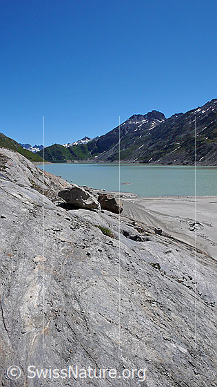 Foto: Oberaarsee mit Sandstrand und abgeschliffenen Felsen im Uferbereich. Im Hintergrund ist das Sidelhorn zu sehen.