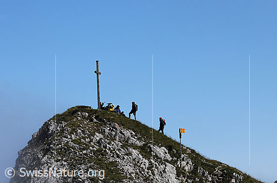Foto: Gipfelrast auf dem Hengst. Die Wanderer lassen sich beim Gipfelkreuz nieder.