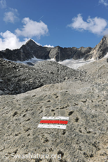 Foto: Markierung Bergweg an Felsplatte am Gletscherrand des Gruebengletschers. Im Hintergrund ist der Gross Diamantstock zu sehen.