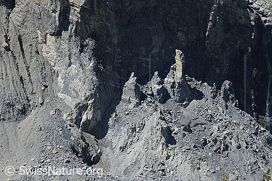 Foto: Der Bergsturz am Eiger. Von der einstigen Schlossplatte sind noch ein paar Felsnadeln übriggeblieben. Viel Geröll aus dem Felssturzgebiet bedeckt des Eis (Toteis) des darunter liegenden Gletschers.