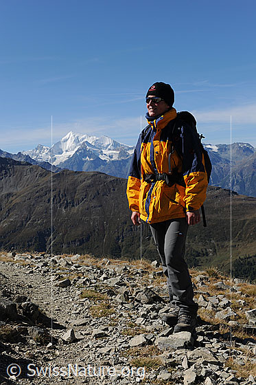 Foto: Wanderin auf Bergweg unterwegs. Im Hintergrund ist das Weisshorn zu sehen.
