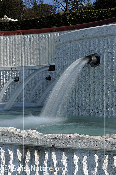 Foto: Langzeitbelichtung: Wasserstrahlen eines Brunnens (Olympisches Museum Lausanne). Dass Wasser trifft spritzend auf der Wasseroberfläche auf.