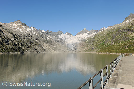 Foto: Das Quellgebiet der Aare: Oberaarsee und Oberaargletscher. In der Wasserfläche des Stausees spiegelt sich die Berglandschaft. 
Der Oberaarsee ist Teil eines Pumpspeicherwerks. Die Pumpspeicherwerke gewinnen für die Speicherung von aus Sonnenlicht und Windkraft erzeugter Energie an Bedeutung.