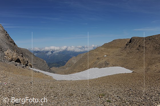 Foto: Blick vom Schnidejoch Richtung N (Saananland).
Die Berglandschaft ist karg. In der weiten Geröllhalde liegt ein Schneefeld.