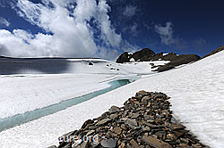 F098236: Hellblauer Wasserstreifen an auftauendem Bergsee