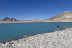 F133647: Alpinistin an Bergsee in karger Berglandschaft